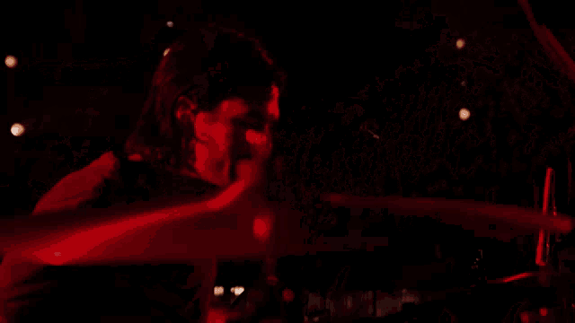 a group of people singing on a stage with red lights behind them