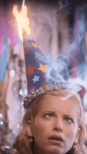 a woman wearing a party hat is holding a lit candle .
