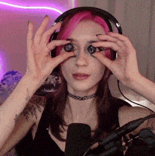 a woman with pink hair is wearing headphones and holding a pair of binoculars in front of a microphone .