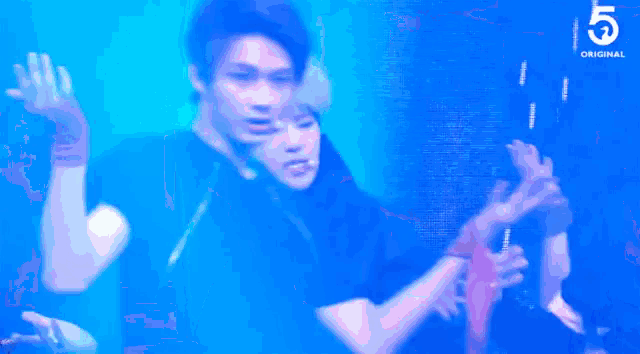 a man in a black shirt is dancing on a stage in front of a crowd with the number 5 in the background .