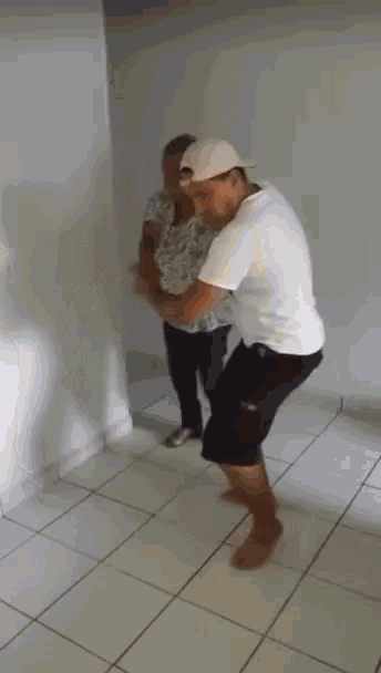 a man in a white hat is holding a woman in a room