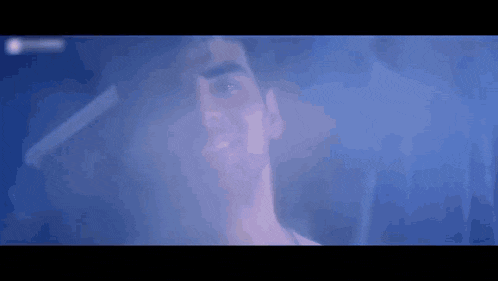 a close up of a man 's face in a dark room with smoke coming out of it .