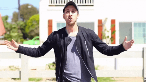 a man with his arms outstretched is wearing a hat