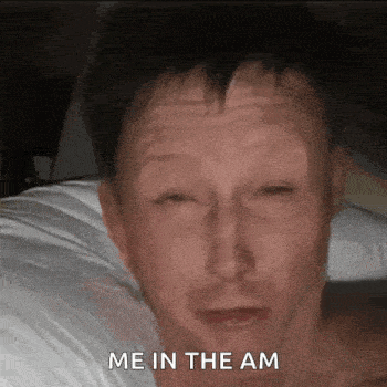 a man is laying in bed with his eyes closed and the words `` me in the am '' on his face .