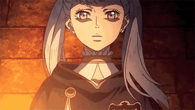 a close up of a girl 's face with a black cape with a black clover on it