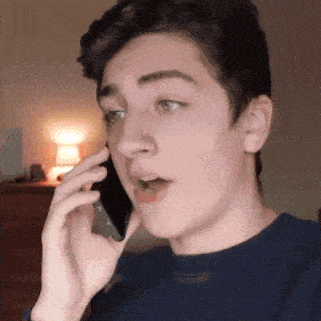 a young man is talking on a cell phone and making a surprised face