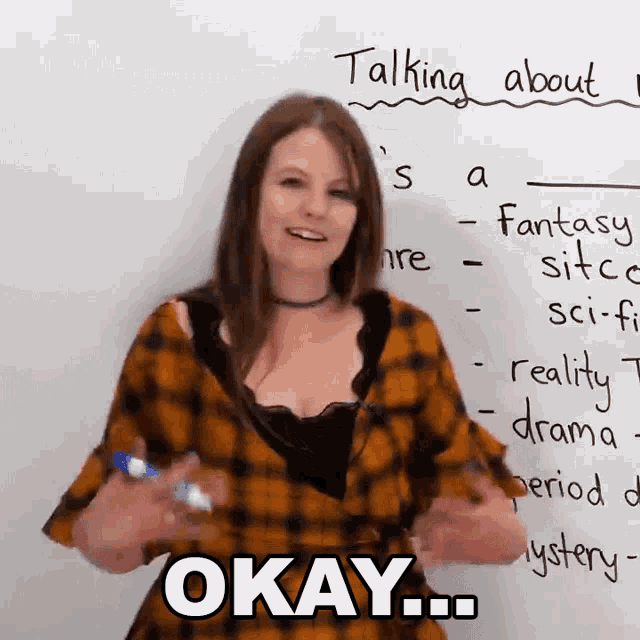 a woman standing in front of a white board that says okay on it