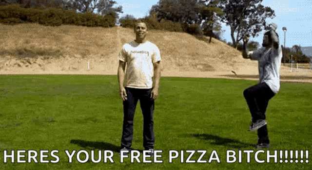 two men standing in a field with the words heres your free pizza bitch !!!