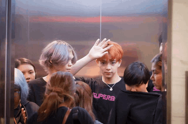 a group of people in an elevator with one wearing a black shirt that says superb