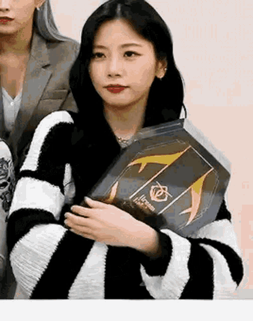 a woman in a black and white striped sweater is holding a trophy .