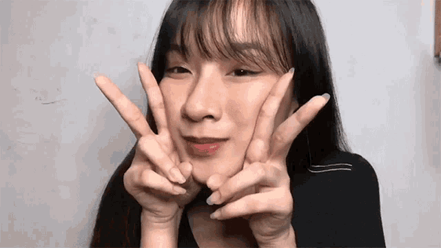 a woman with long hair is making a peace sign with her hands