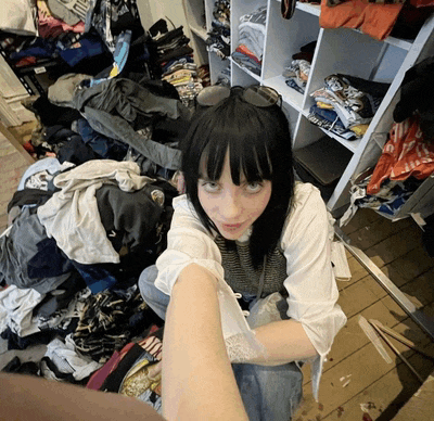a woman sitting in front of a pile of clothes including a shirt that says ' i love you '