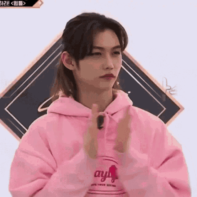a person wearing a pink hoodie is clapping their hands .