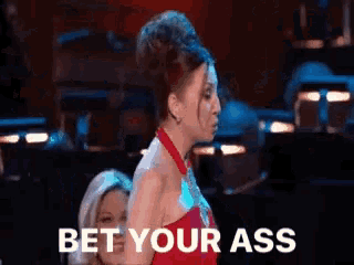 a woman in a red dress is standing in front of a sign that says " bet your ass "