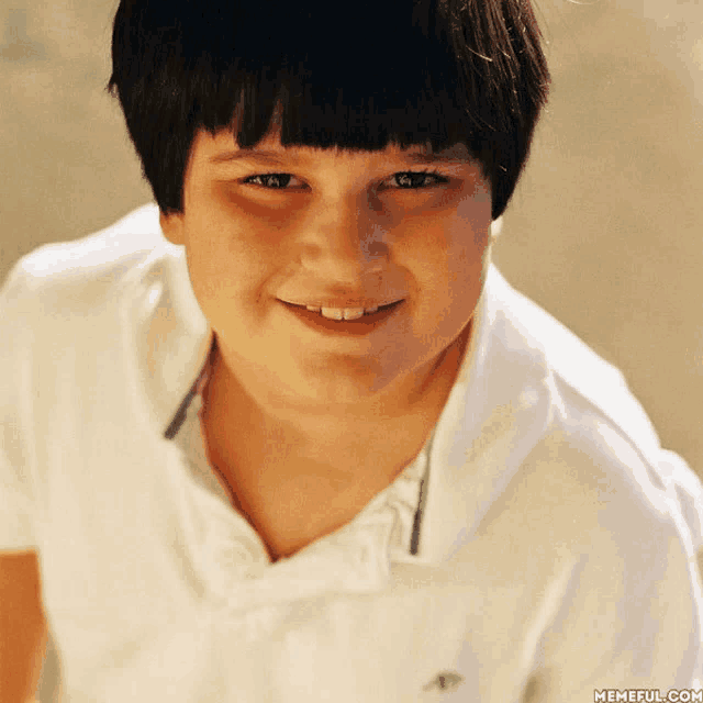 a young boy wearing a white shirt with an eagle on the collar