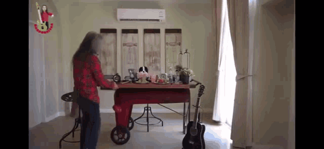 a woman is standing in front of a table with a guitar on it in a living room .