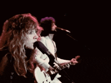 a woman singing into a microphone next to a man