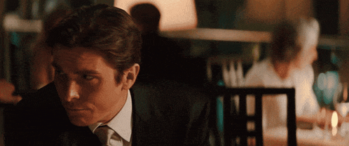 a man in a suit and tie is sitting at a table in a restaurant