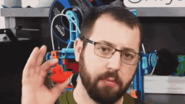 a man with a beard and glasses is holding a toy in his hand