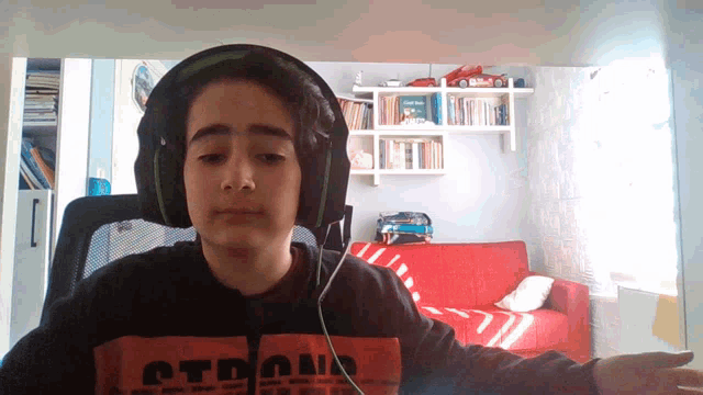 a young boy wearing headphones and an orange shirt with the word strong on it