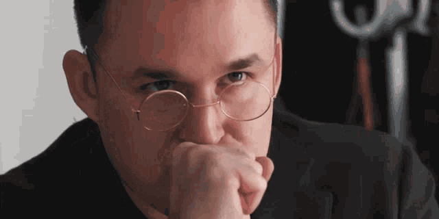 a close up of a man wearing glasses and a black suit