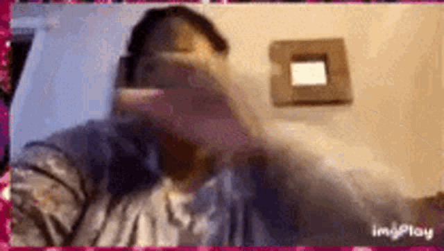 a woman is covering her face with her hand while looking at a mirror .