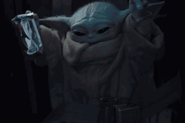 a baby yoda is holding a package of food