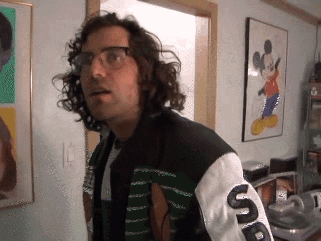 a man wearing glasses and a jacket that says supreme on the sleeve