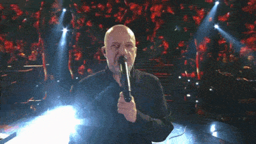 a man singing into a microphone in front of a crowd