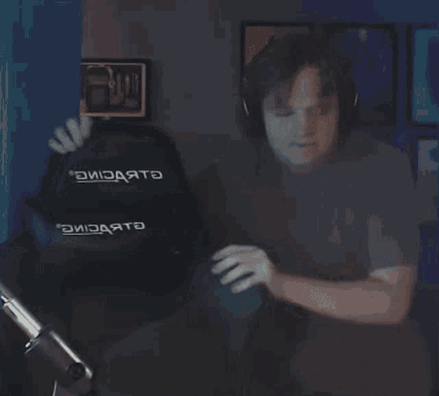 a man wearing headphones is playing a video game in front of a chair that says ' aviadate ' on it