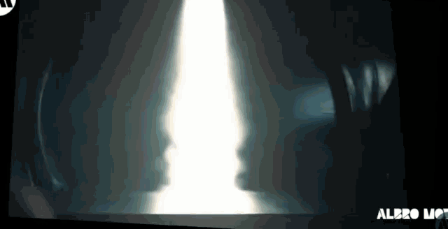 a person is standing in a dark room with a light coming out of the ceiling .