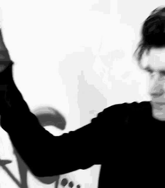 a man is standing in front of a white wall with his arms outstretched .