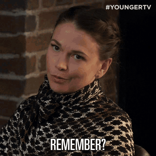 a woman wearing a turtleneck sweater says " remember " in front of a brick wall