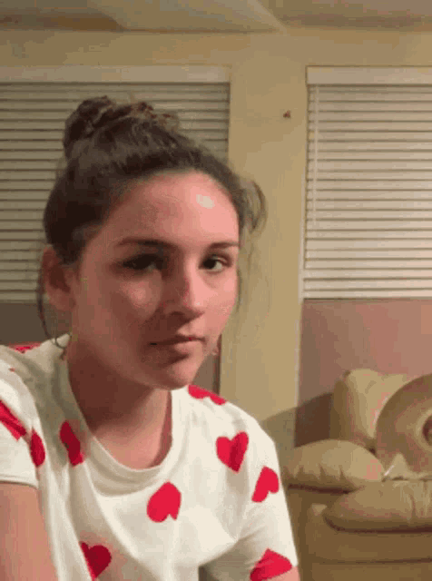 a girl with a bun on her head is wearing a shirt with red hearts on it