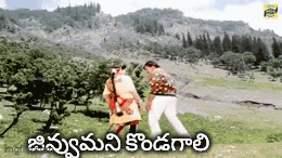 a man and a woman dancing in a field with mountains in the background