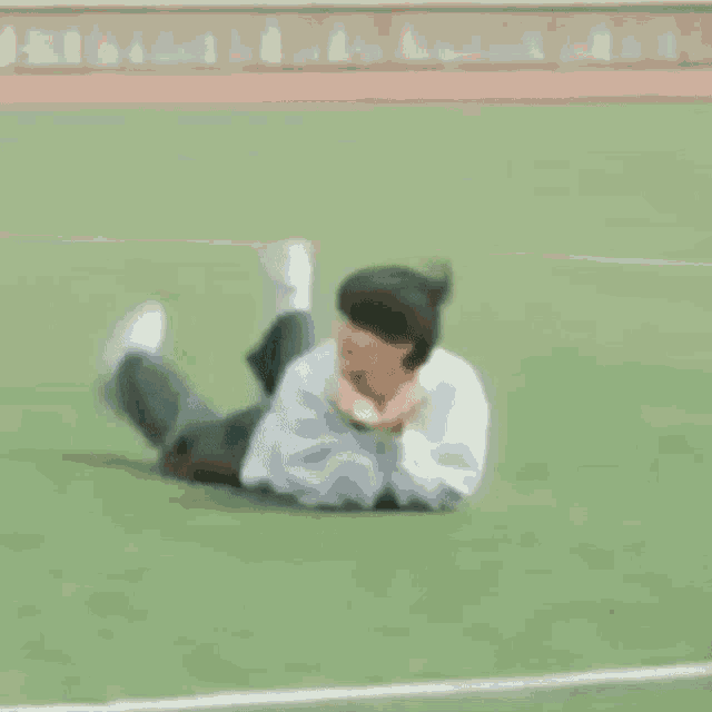 a person is laying on their stomach on a lush green field .