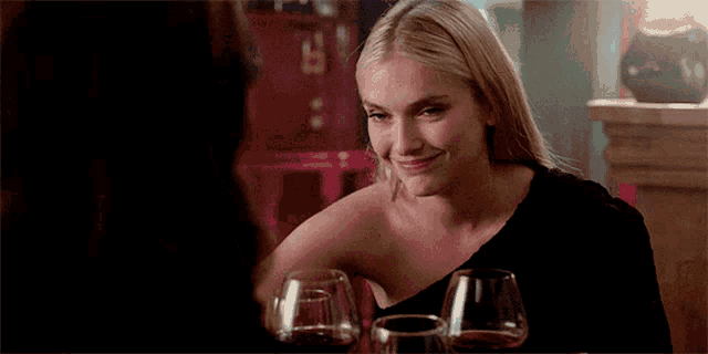 a woman sits at a table with two glasses of wine