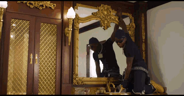 a man in a black shirt is looking at himself in the mirror