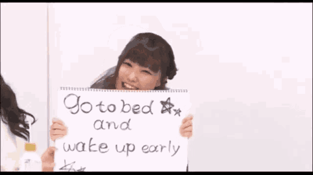 a girl in a school uniform is holding a sign that says go to bed and wake up early