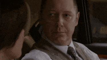 a man in a suit and tie is sitting in a car with the words " i will " written in red