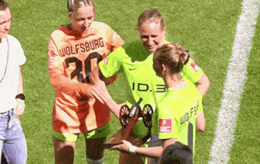 a woman in a wolfsburg jersey shakes hands with another woman on a soccer field