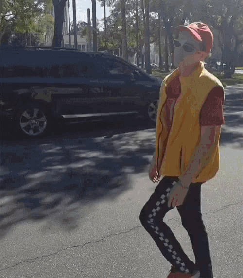 a person wearing sunglasses and a yellow vest is walking down the street