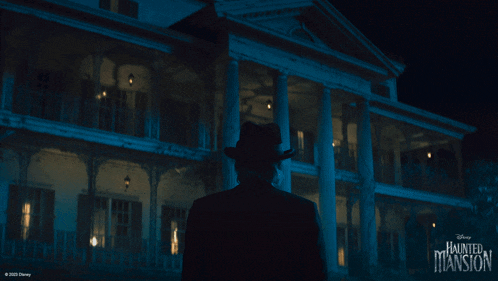 a man in a hat is standing in front of a haunted mansion