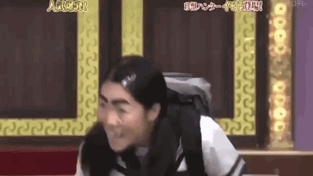 a woman in a school uniform is making a funny face while wearing a backpack .