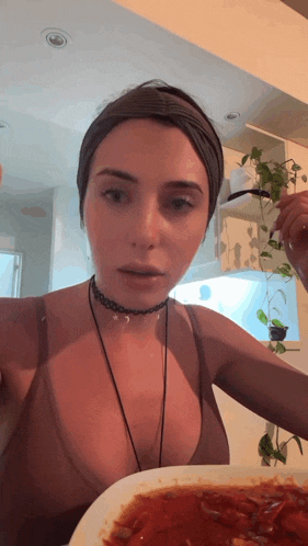 a woman wearing a choker is eating a plate of food with a fork