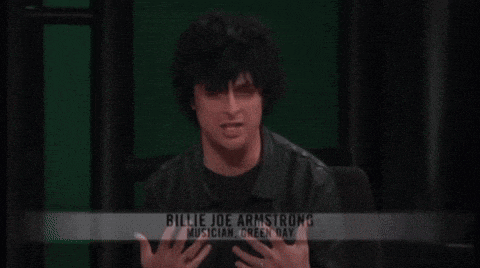 a man named billie joe armstrong is sitting in front of a green screen