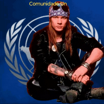 a man in a bandana sits in front of a comunidade un sign