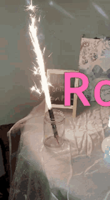 a sparkler in a jar with the letter r in pink