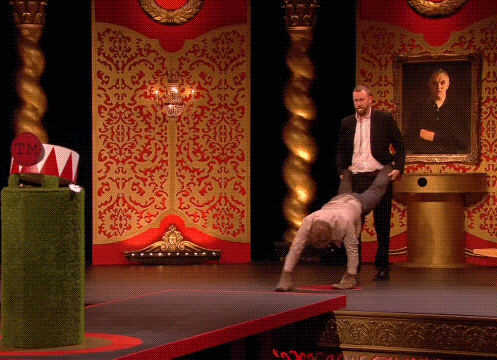 a man in a suit is holding a woman upside down