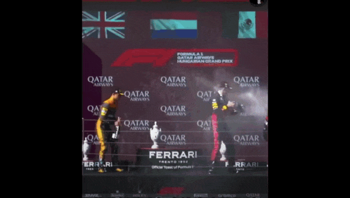 a man is standing on a podium with qatar airways written on the wall behind him